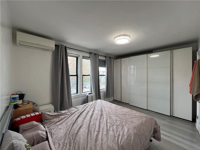 bedroom with light wood-type flooring and a wall unit AC