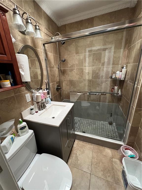 bathroom featuring ornamental molding, walk in shower, tile patterned floors, and vanity