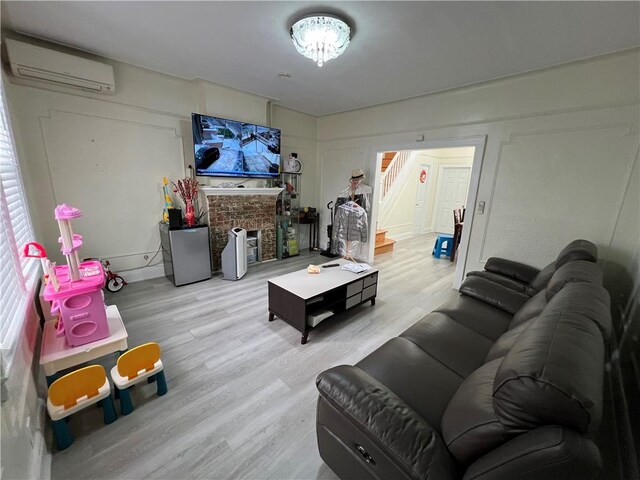 living room featuring light wood-type flooring and a wall unit AC