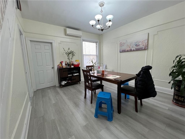 dining area with an AC wall unit, light hardwood / wood-style floors, and a chandelier