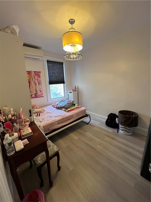 bedroom with an AC wall unit and wood-type flooring