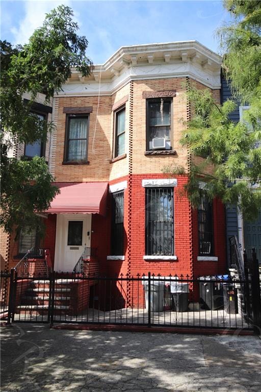 view of front of house featuring brick siding, a fenced front yard, and cooling unit