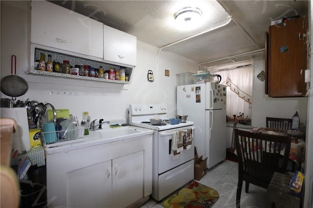 kitchen featuring a textured ceiling, white appliances, a sink, and white cabinetry