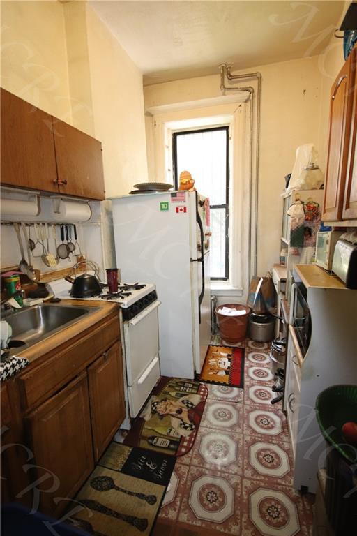 kitchen with white gas range, brown cabinets, and a sink