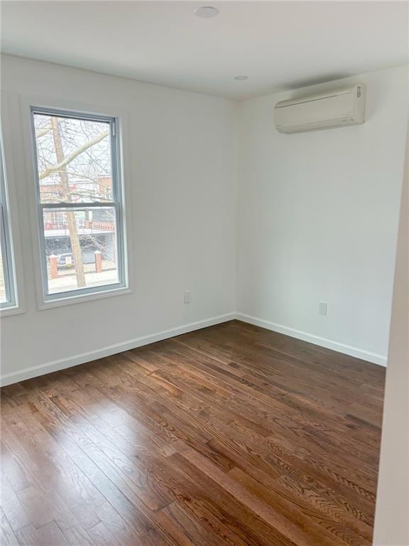 unfurnished room featuring a wall mounted air conditioner, dark hardwood / wood-style floors, and plenty of natural light