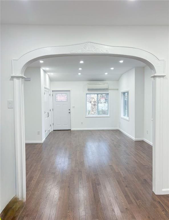 unfurnished living room with dark hardwood / wood-style floors, decorative columns, and a wall mounted AC