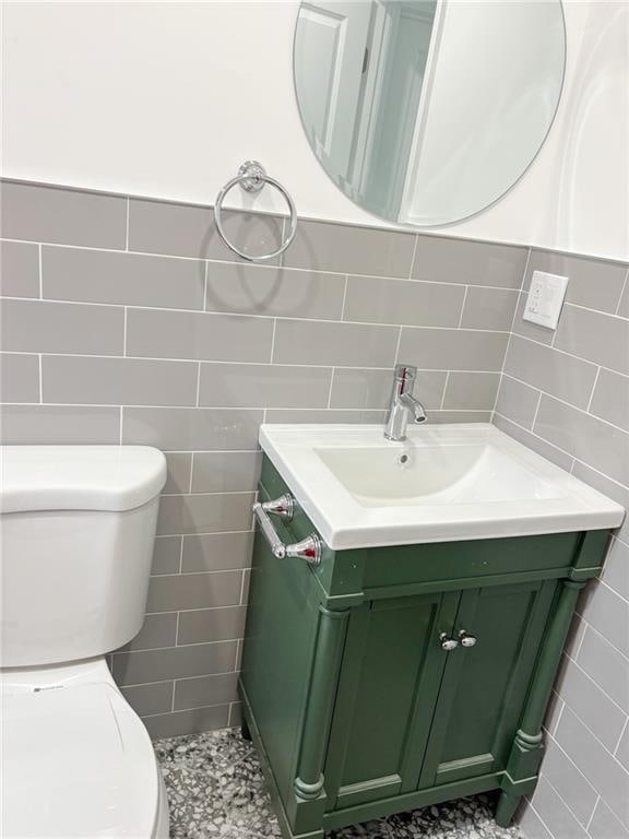 bathroom with vanity, toilet, and tile walls