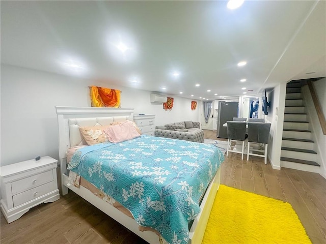 bedroom with stainless steel fridge, wood-type flooring, and a wall mounted air conditioner