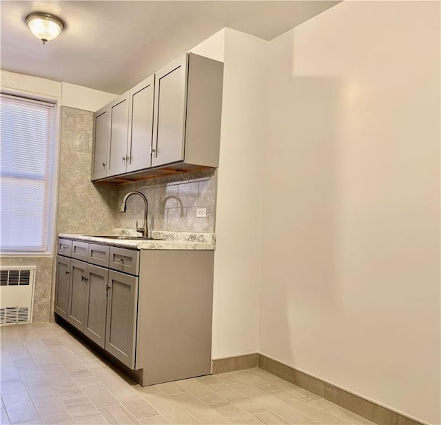 kitchen featuring decorative backsplash, sink, gray cabinetry, light tile patterned floors, and radiator heating unit