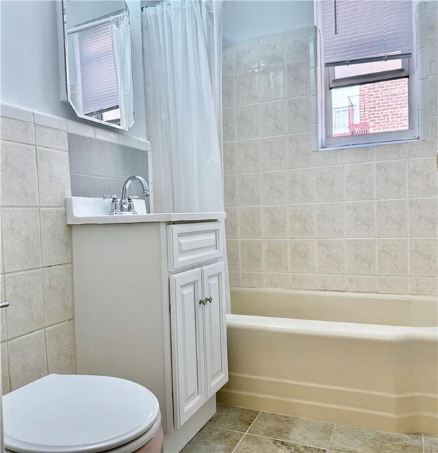 full bathroom featuring toilet, vanity, tile walls, tile patterned floors, and shower / bathtub combination with curtain