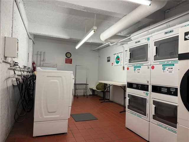 laundry room featuring separate washer and dryer, stacked washer and clothes dryer, and dark tile patterned flooring