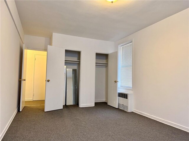 unfurnished bedroom with radiator heating unit and dark colored carpet