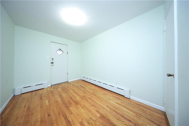 empty room with a baseboard radiator and light hardwood / wood-style floors