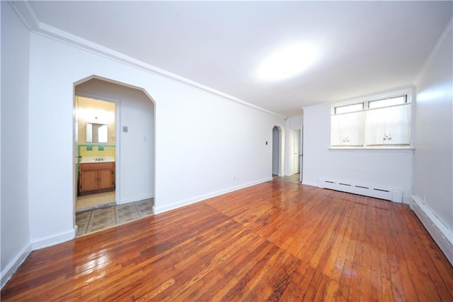 unfurnished room with crown molding, wood-type flooring, and baseboard heating