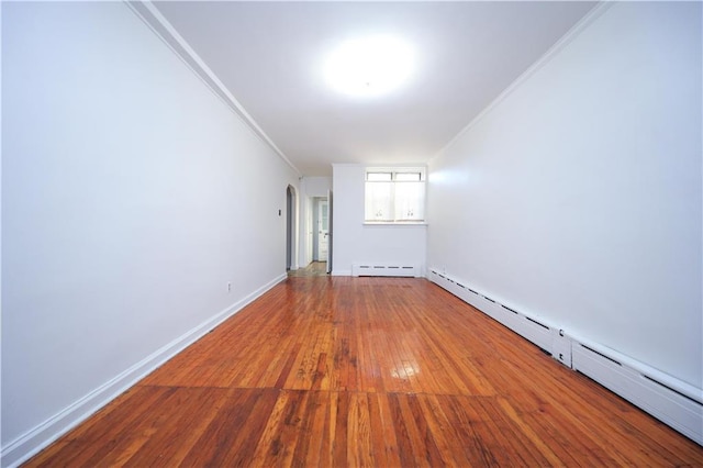 spare room featuring a baseboard radiator, ornamental molding, and hardwood / wood-style floors