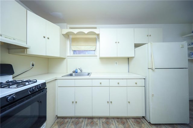 kitchen featuring white refrigerator, gas range, sink, and white cabinetry