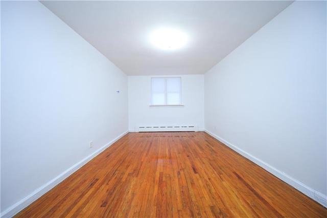 spare room featuring wood-type flooring and baseboard heating