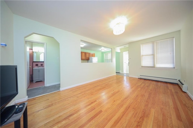 unfurnished living room with a baseboard heating unit and light wood-type flooring