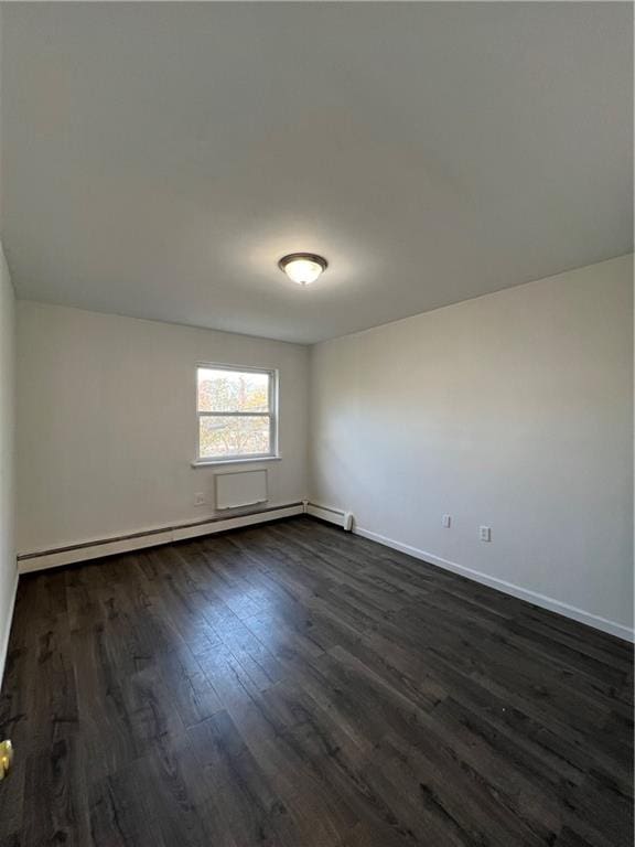 spare room featuring dark wood-type flooring and a baseboard radiator