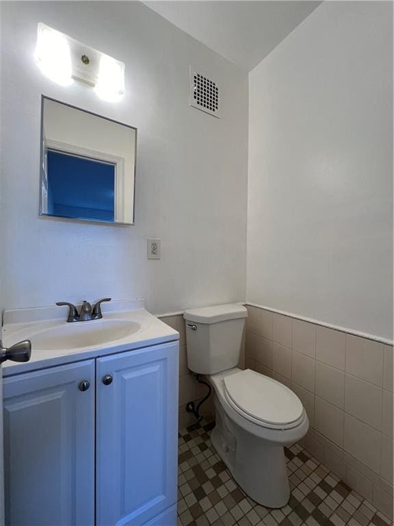 bathroom featuring vanity, toilet, tile patterned flooring, and tile walls