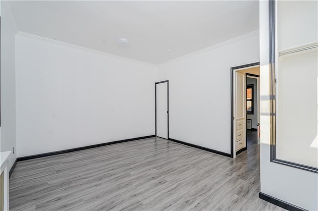 spare room featuring baseboards, wood finished floors, and crown molding