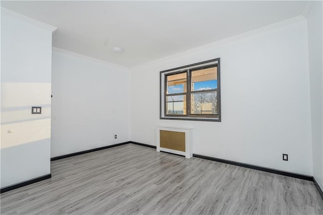 empty room with wood finished floors, baseboards, and ornamental molding