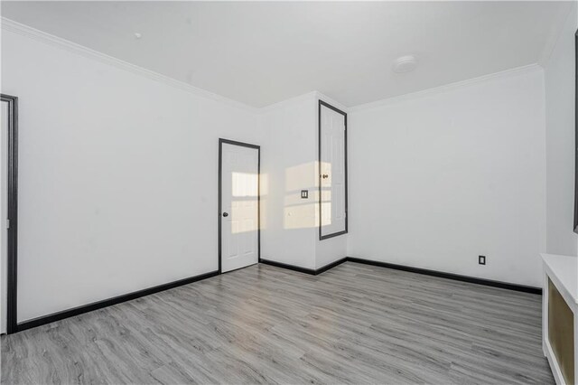 empty room featuring light wood-type flooring and ornamental molding