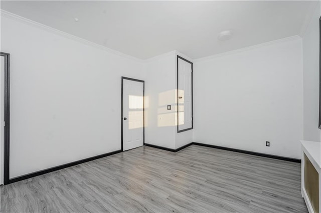 empty room with light wood-type flooring, crown molding, and baseboards