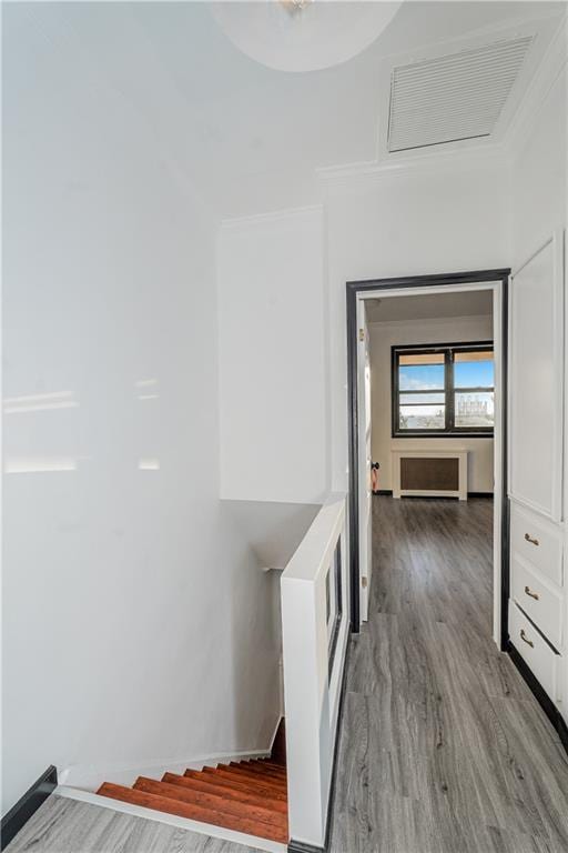 hallway featuring visible vents, ornamental molding, and wood finished floors