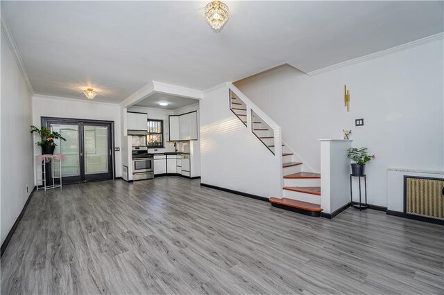 unfurnished living room featuring crown molding, hardwood / wood-style floors, and radiator heating unit