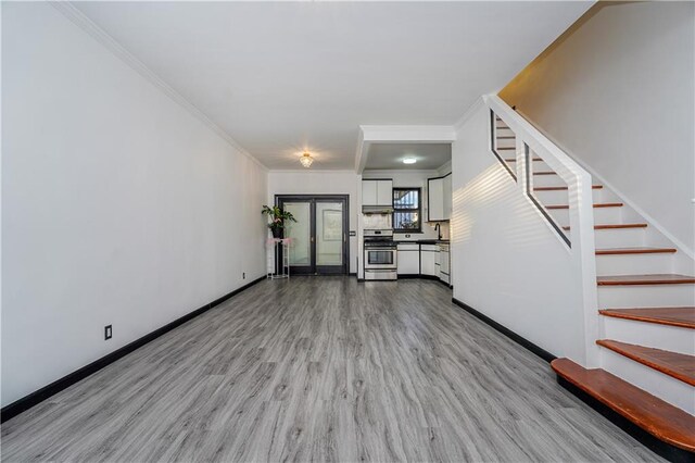 unfurnished living room with crown molding and light hardwood / wood-style floors