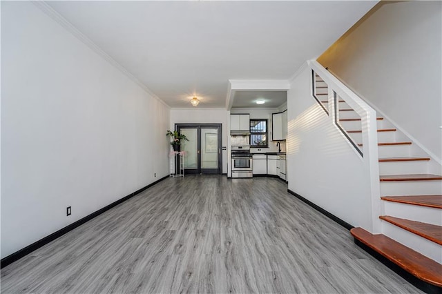 unfurnished living room with baseboards, light wood-style floors, stairs, and crown molding