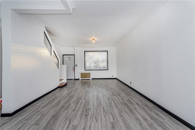 spare room with wood finished floors, stairs, baseboards, and ornamental molding