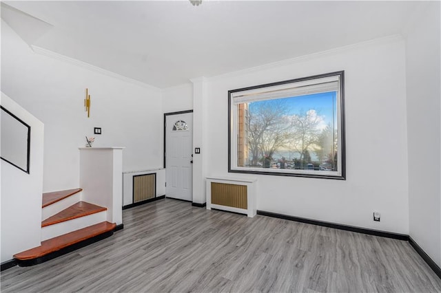 foyer entrance with crown molding, radiator heating unit, wood finished floors, and baseboards