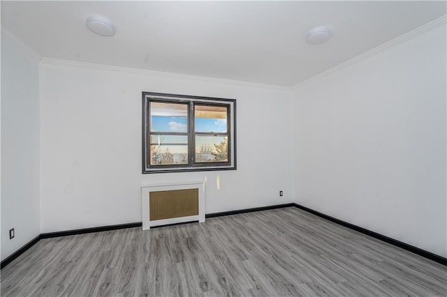 spare room with baseboards, wood finished floors, and crown molding