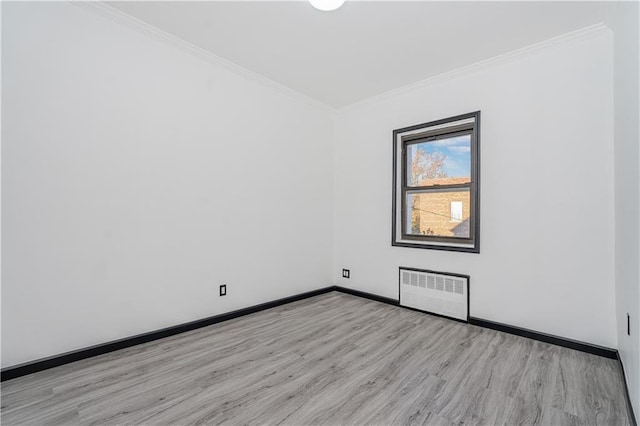 empty room with light wood finished floors, baseboards, radiator heating unit, and crown molding