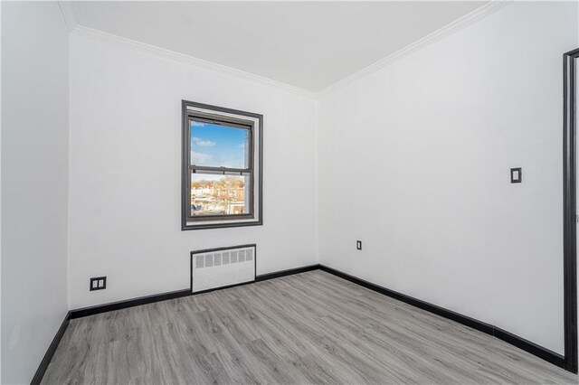 empty room featuring radiator, ornamental molding, and light hardwood / wood-style flooring