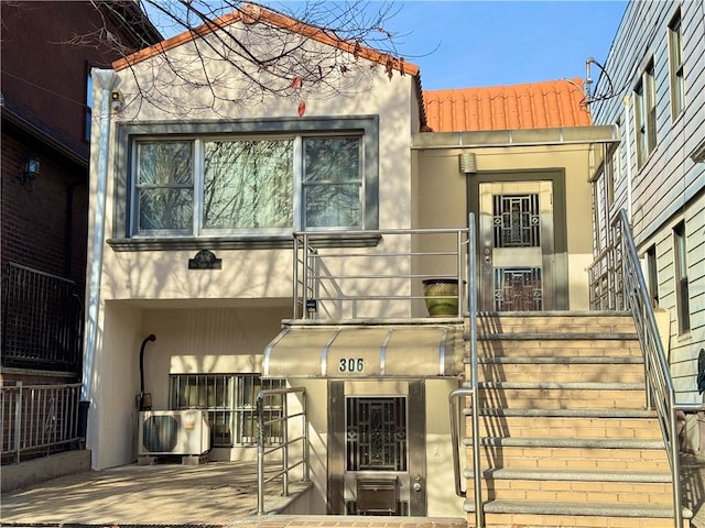 entrance to property with stucco siding, a tile roof, and ac unit