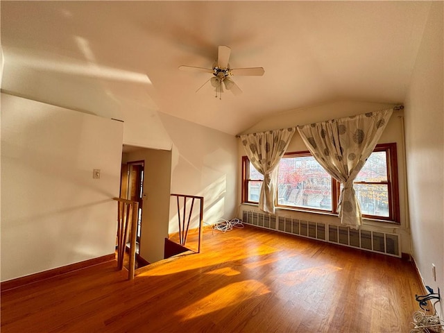 additional living space featuring hardwood / wood-style flooring, radiator heating unit, ceiling fan, and vaulted ceiling