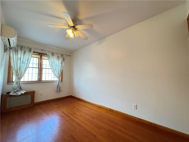 spare room featuring wood-type flooring, an AC wall unit, and ceiling fan