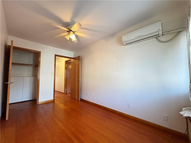 unfurnished bedroom featuring wood-type flooring, a wall unit AC, and ceiling fan