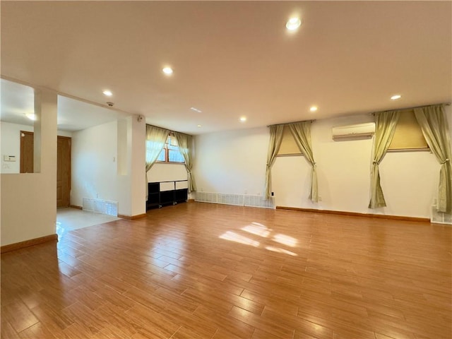 basement featuring light hardwood / wood-style flooring and an AC wall unit