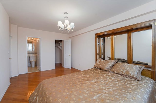 bedroom featuring connected bathroom, a notable chandelier, wood finished floors, and a spacious closet