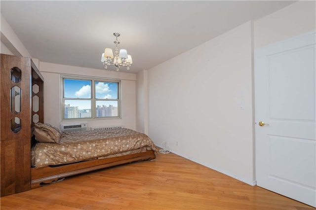 bedroom featuring a wall mounted air conditioner, a notable chandelier, and light wood-style flooring