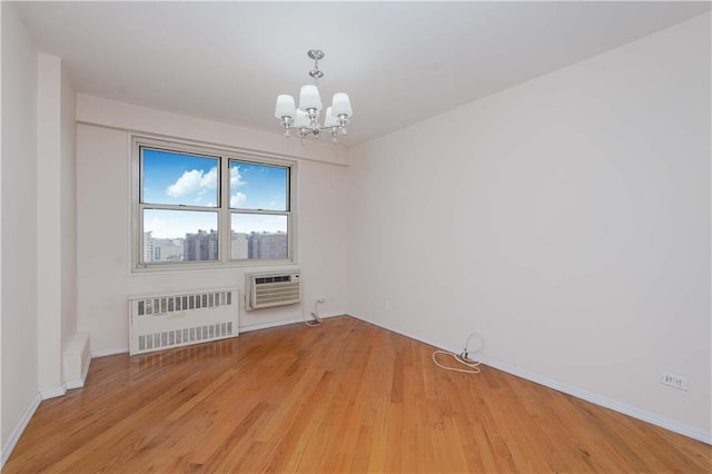 unfurnished room with radiator, baseboards, a chandelier, a wall mounted air conditioner, and light wood-type flooring