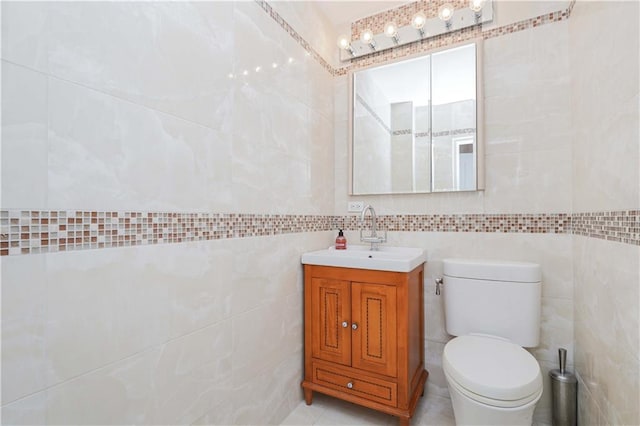 bathroom featuring vanity, tile walls, and toilet