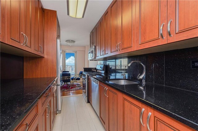 kitchen with appliances with stainless steel finishes, tasteful backsplash, dark stone countertops, and sink