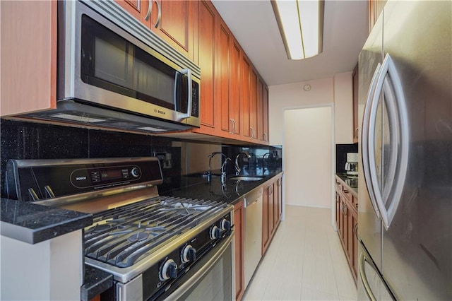 kitchen with brown cabinets, a sink, dark stone countertops, stainless steel appliances, and decorative backsplash