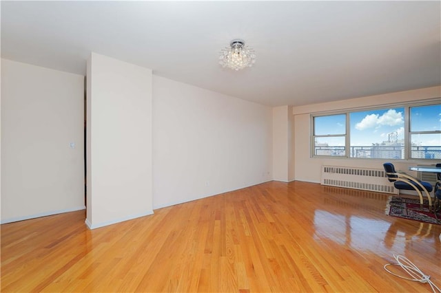 unfurnished living room featuring radiator and light wood-style floors