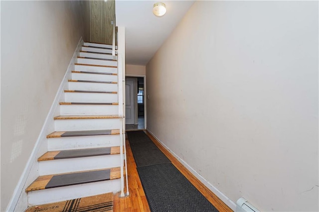 staircase with hardwood / wood-style floors and baseboard heating